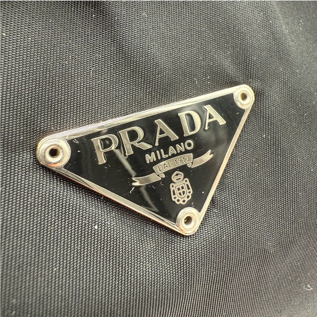 https://cdn.shopify.com/s/files/1/0564/9376/8855/files/Prada_Handtasche_rechteckig_aus_Nylon_schwarz_vintage_luxury_handbag_4346.webp?v=1744967277