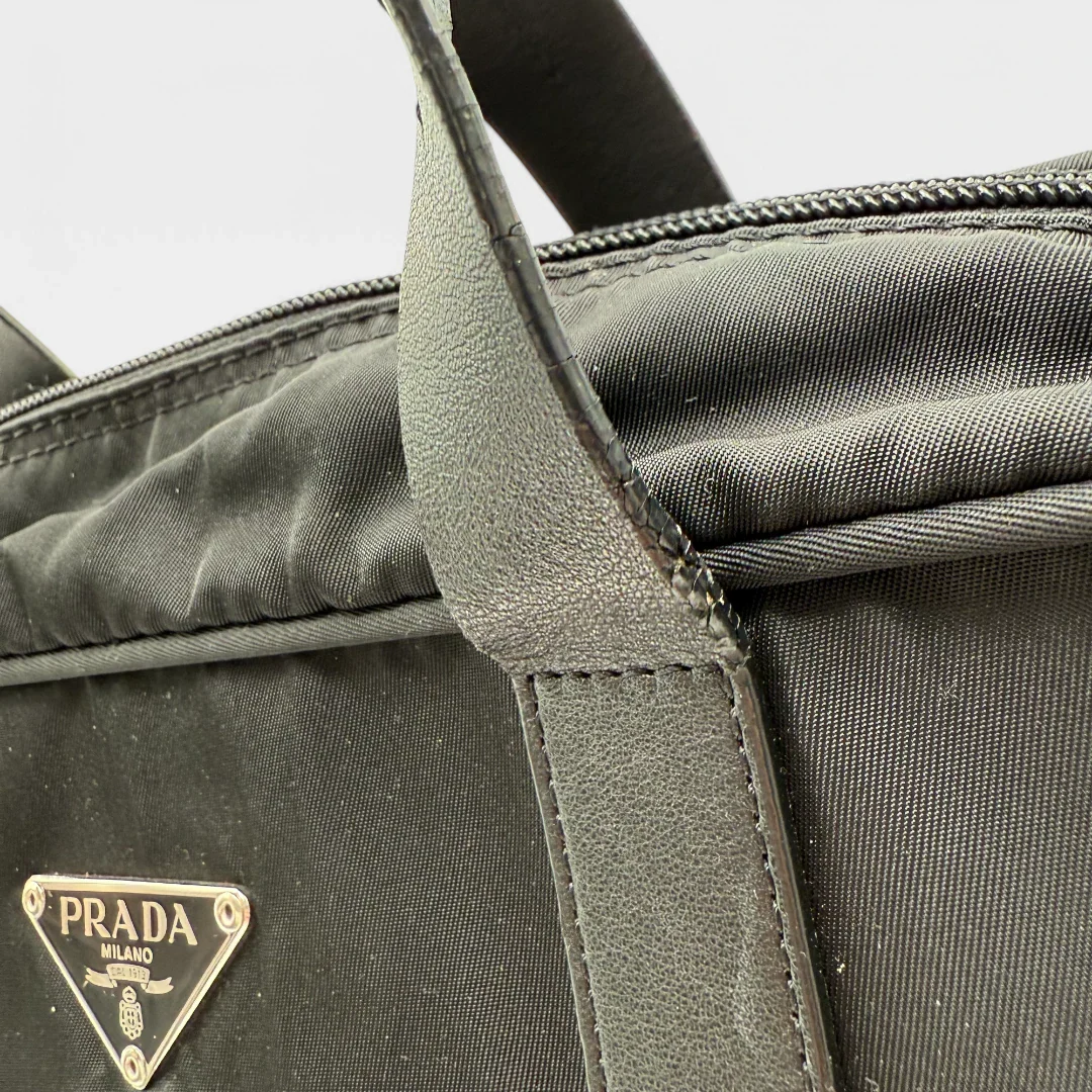 https://cdn.shopify.com/s/files/1/0564/9376/8855/files/Prada_Handtasche_rechteckig_aus_Nylon_schwarz_vintage_luxury_handbag_4348.webp?v=1744967277