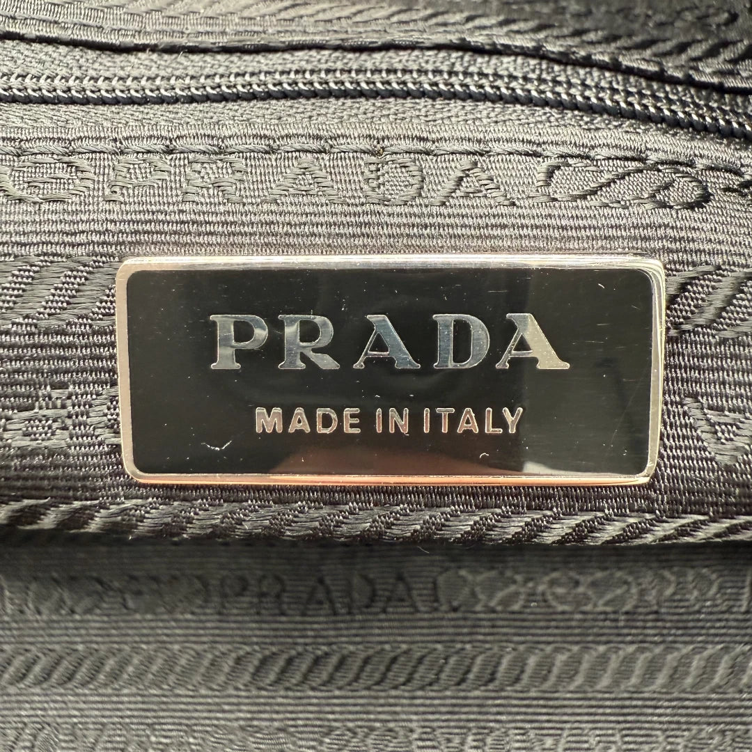 https://cdn.shopify.com/s/files/1/0564/9376/8855/files/Prada_Handtasche_rechteckig_aus_Nylon_schwarz_vintage_luxury_handbag_4351.webp?v=1744967277