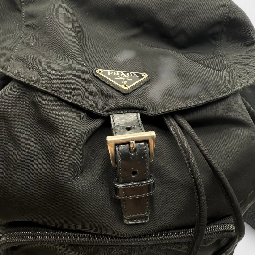 https://cdn.shopify.com/s/files/1/0564/9376/8855/files/Prada_Rucksack_mit_Schnalle_aus_Nylon_schwarz_second_hand_designer_backpack3169.webp?v=1753348226
