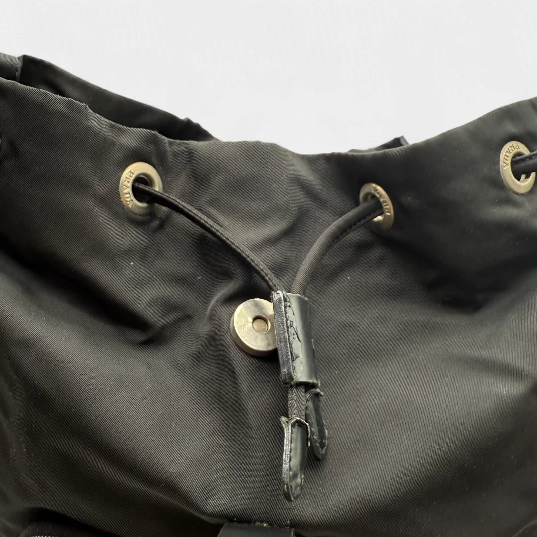 https://cdn.shopify.com/s/files/1/0564/9376/8855/files/Prada_Rucksack_mit_Schnalle_aus_Nylon_schwarz_second_hand_designer_backpack3172.webp?v=1753348226