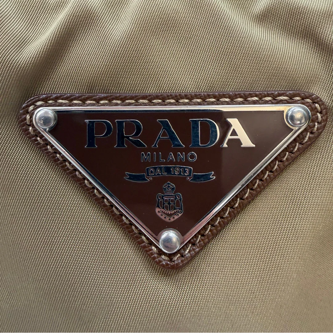 https://cdn.shopify.com/s/files/1/0564/9376/8855/files/Prada_Schultertasche_Hobo_Croissant_aus_Nylon_beige_vintage7744.webp?v=1780487480
