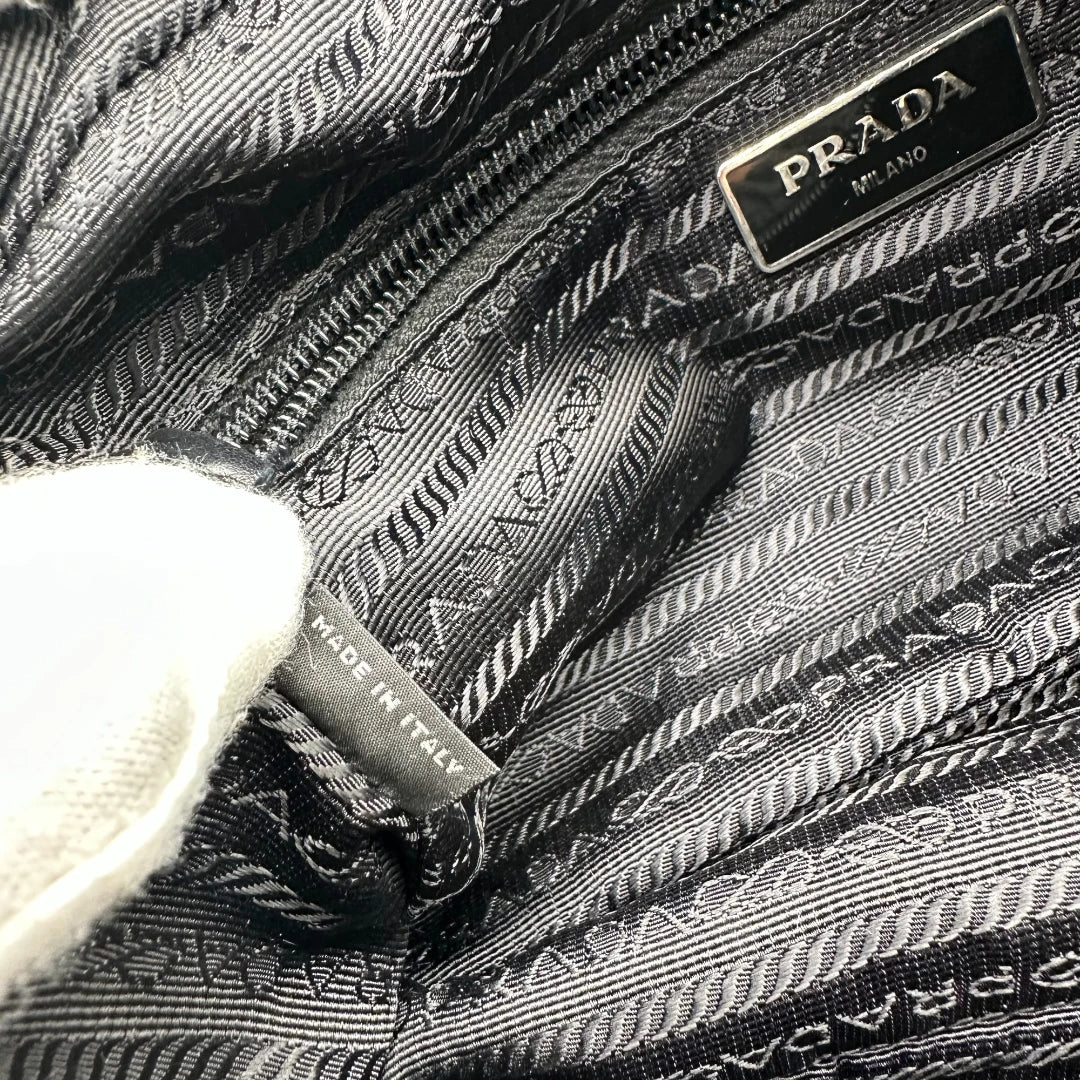https://cdn.shopify.com/s/files/1/0564/9376/8855/files/Prada_Umhangetasche_AW18_mit_Nieten_aus_Nylon_schwarz_vintage_crossbody8186.webp?v=1758632969
