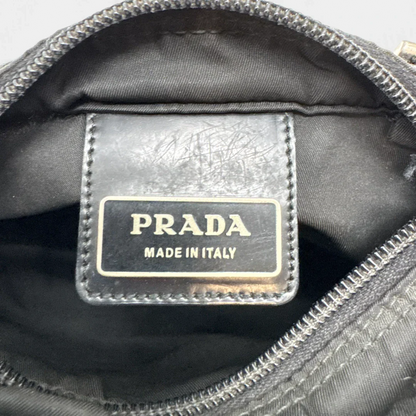 https://cdn.shopify.com/s/files/1/0564/9376/8855/files/Prada_Umhangetasche_basic_aus_Nylon_schwarz_vintage_luxury_crossbody3013.webp?v=1757027912