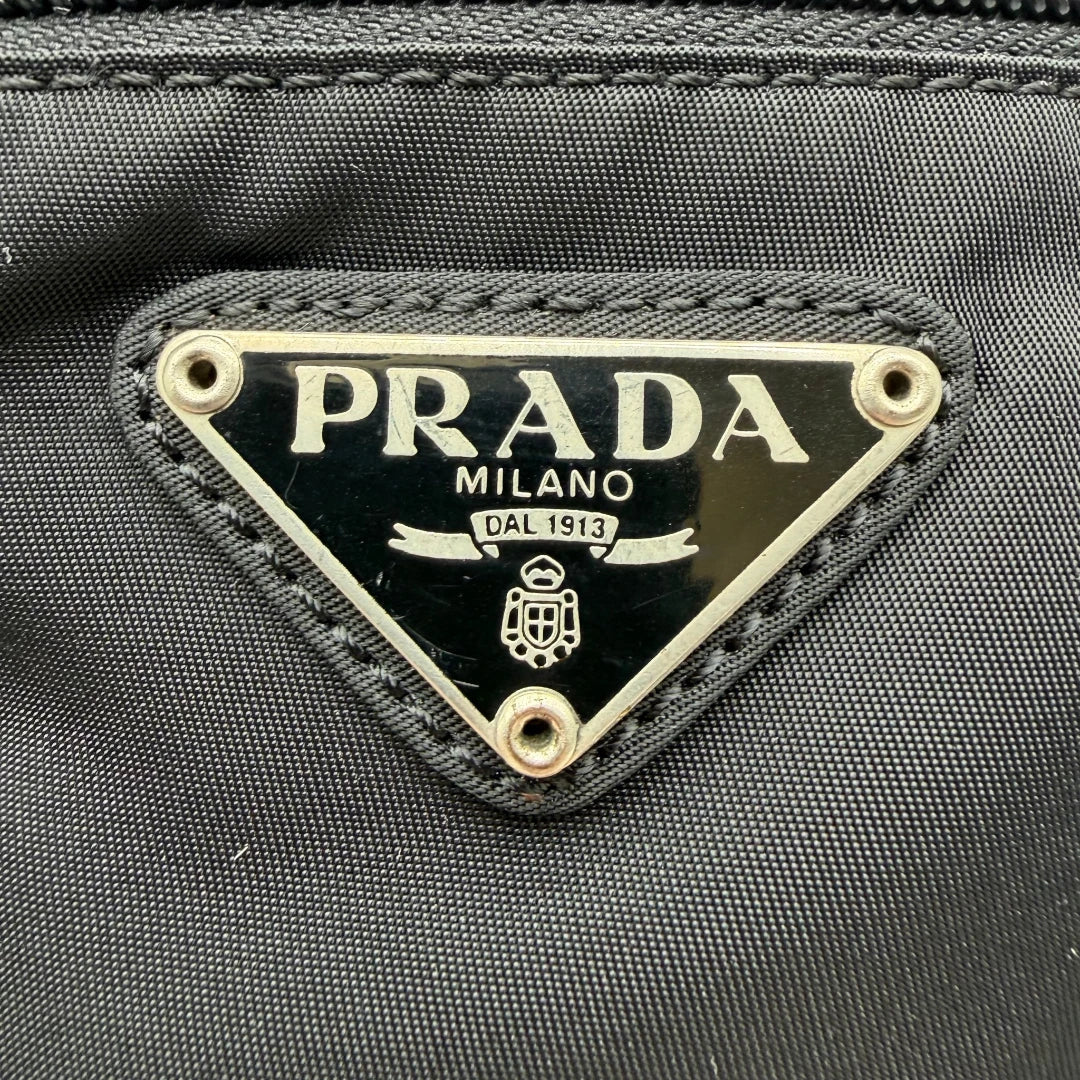 https://cdn.shopify.com/s/files/1/0564/9376/8855/files/Prada_Umhangetasche_basic_small_aus_Nylon_schwarz_vintage8294.webp?v=1781084674