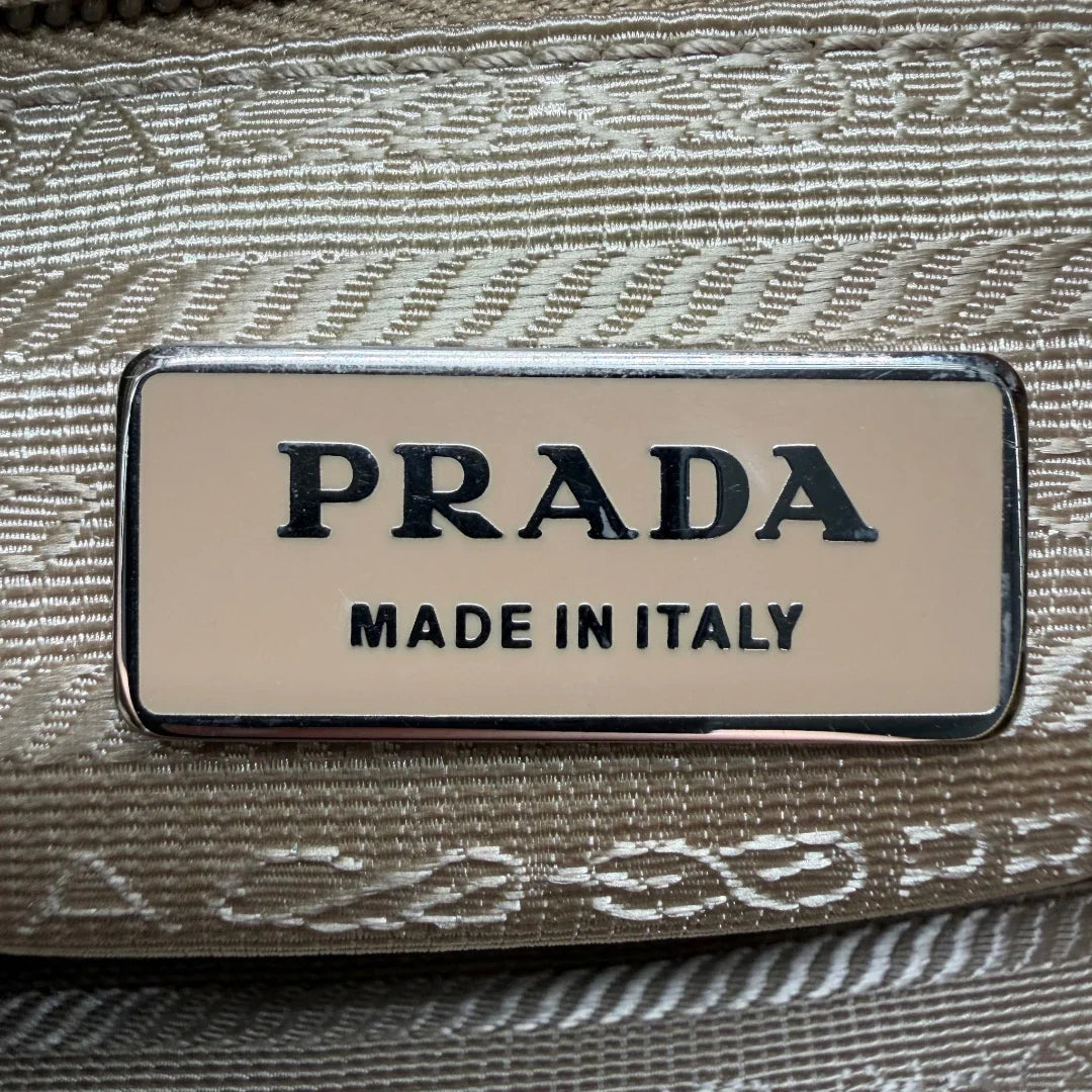 https://cdn.shopify.com/s/files/1/0564/9376/8855/files/Prada_Umhangetasche_rechteckig_small_aus_Nylon_hellbraun_15.webp?v=1782311805