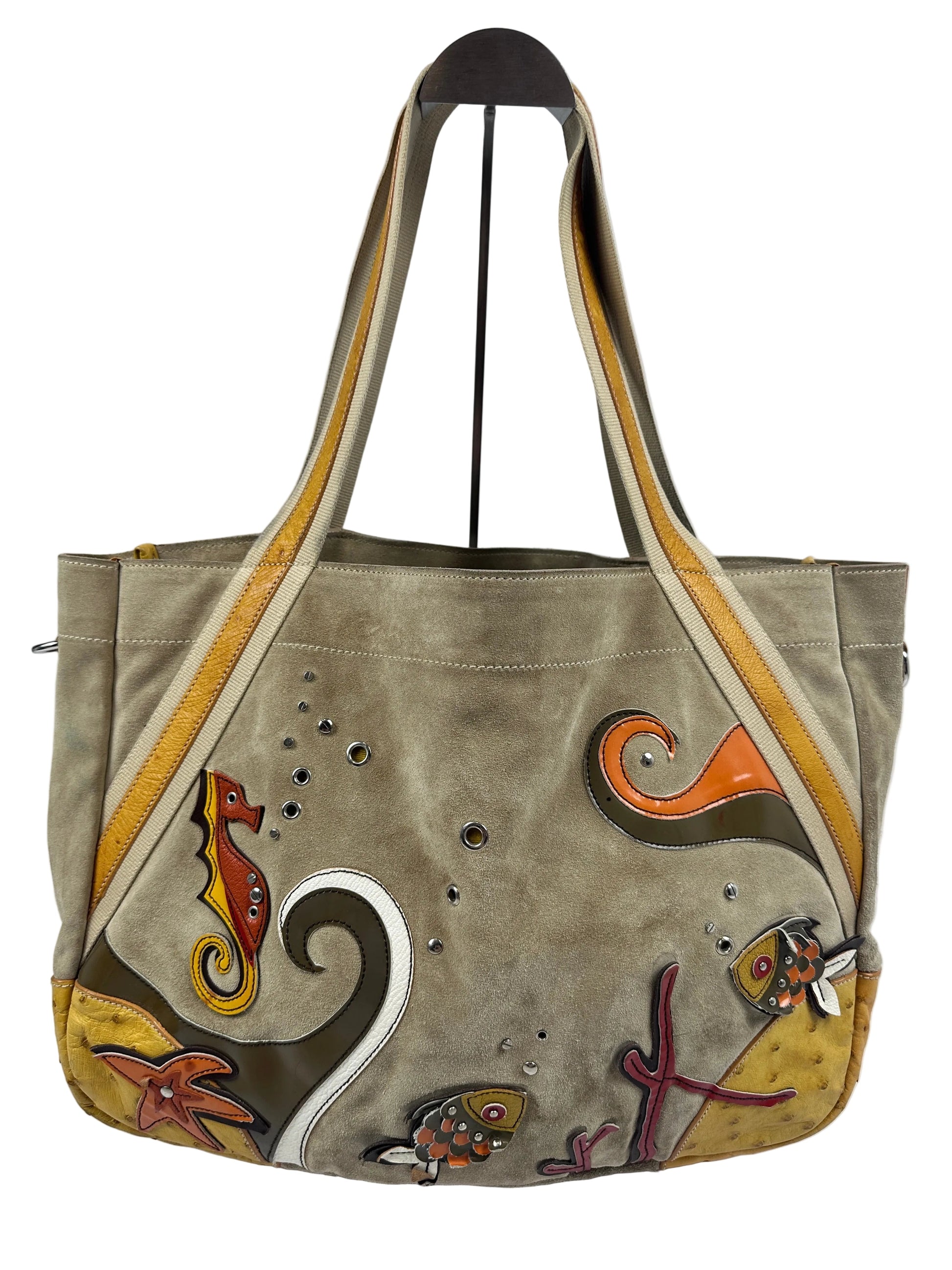 A taupe suede shoulder bag with hand-painted sea life motifs, including a turtle, starfish, and fish, in orange, yellow, brown, and white. The bag features a wide shoulder strap with beige and yellow stripes and is photographed against a plain light gray background.