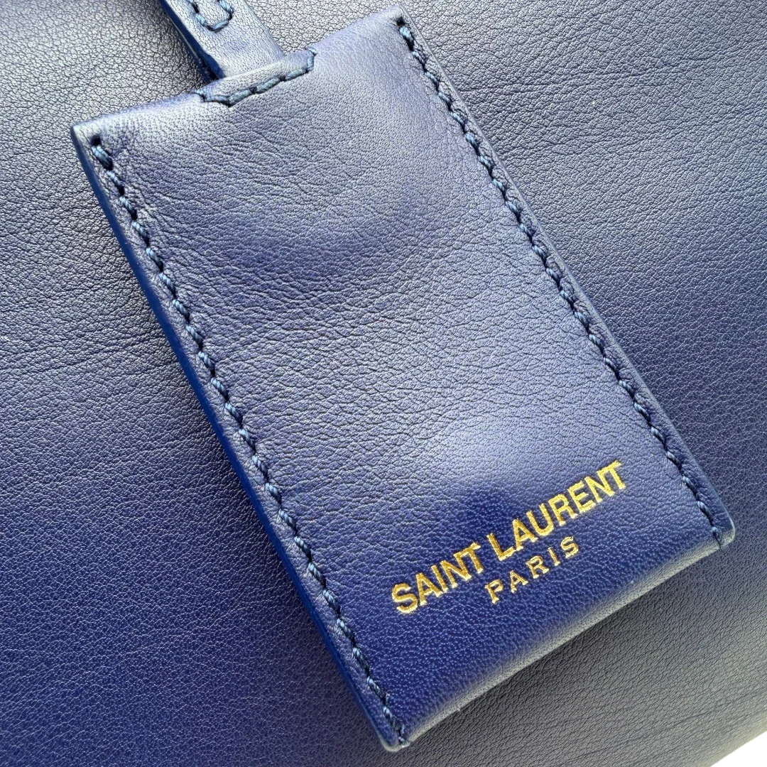 https://cdn.shopify.com/s/files/1/0564/9376/8855/files/Saint_Laurent_Handtasche_Cabbas_mit_Umhangegurt_aus_Leder_blau_vintage2613.webp?v=1773312218