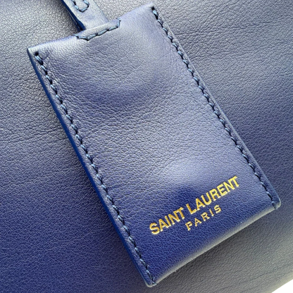 https://cdn.shopify.com/s/files/1/0564/9376/8855/files/Saint_Laurent_Handtasche_Cabbas_mit_Umhangegurt_aus_Leder_blau_vintage2613.webp?v=1773312218