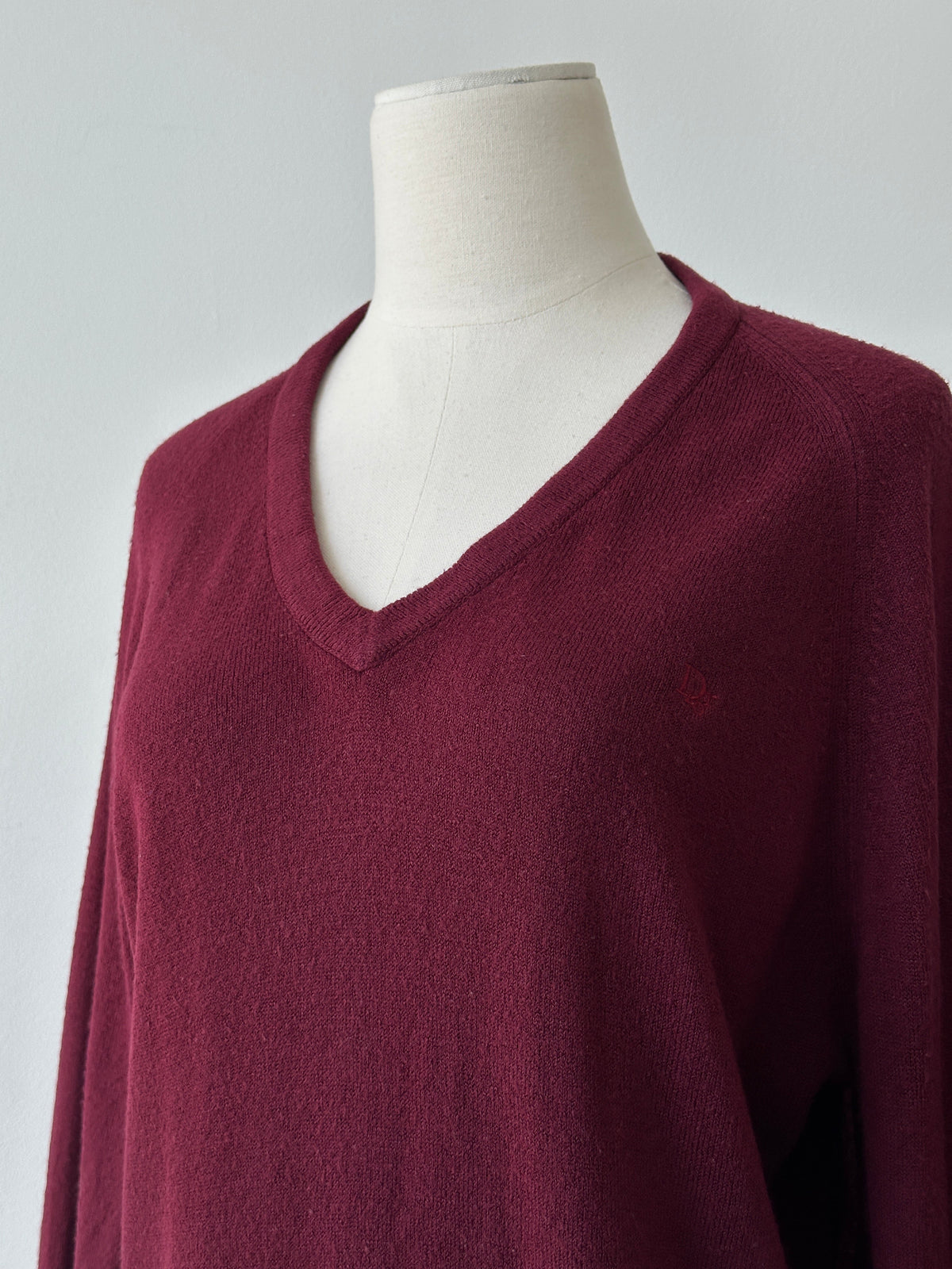 Christian Dior 1990s V-neck logo jumper in gray, featuring the iconic Dior logo on the front, displayed on a hanger.