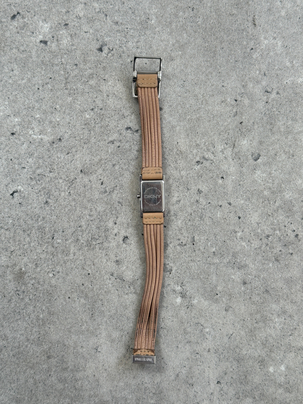 Donna Karran DKNY 2000s leather rectangular quartz watch with silver-tone dial and black leather strap, close-up view.