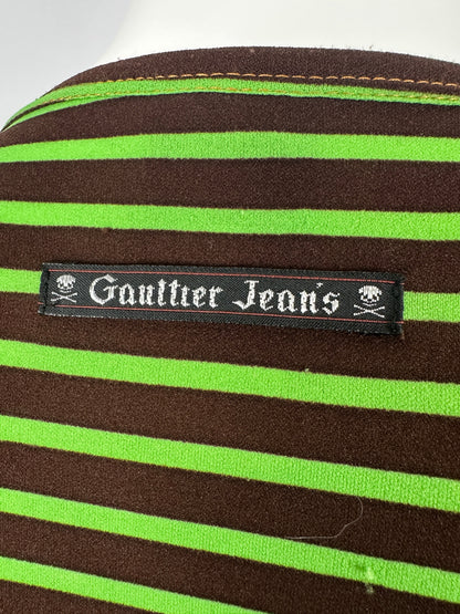 Close-up of a Gaultier Jeans label on a brown and green striped fabric.