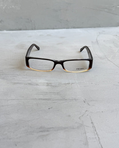 Prada Clear Lens Brown Frame Glasses-on a concrete background
